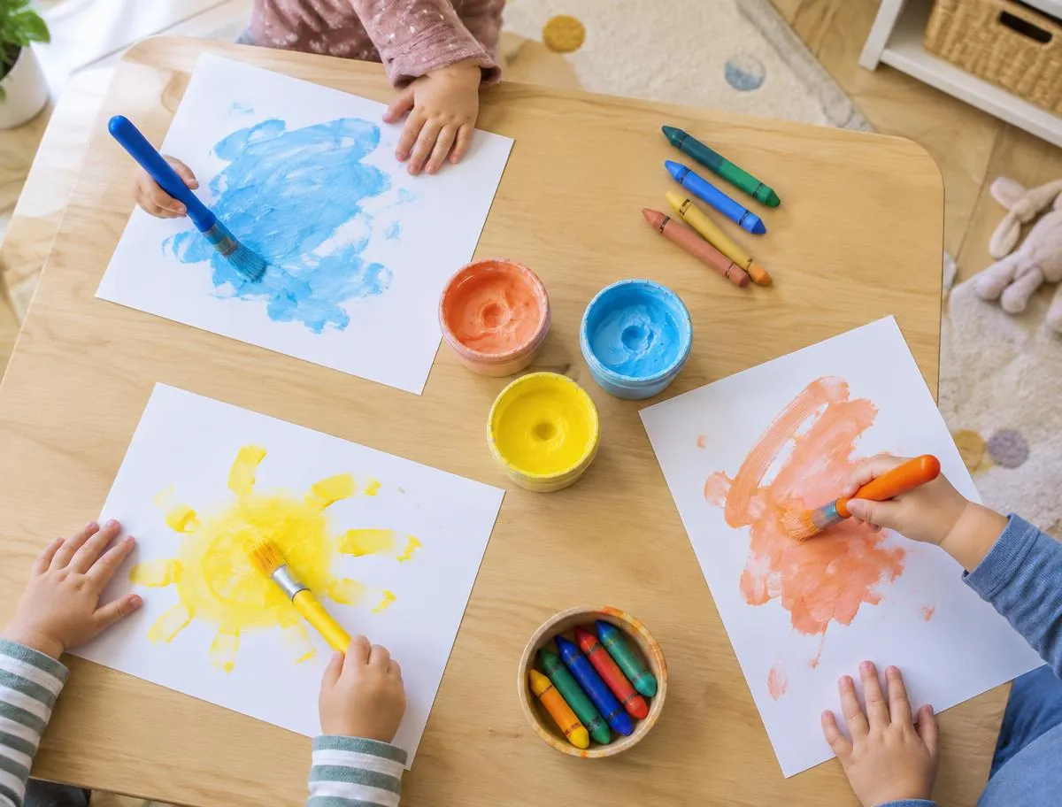 Toddlers' hands painting with brushes at a children's art table